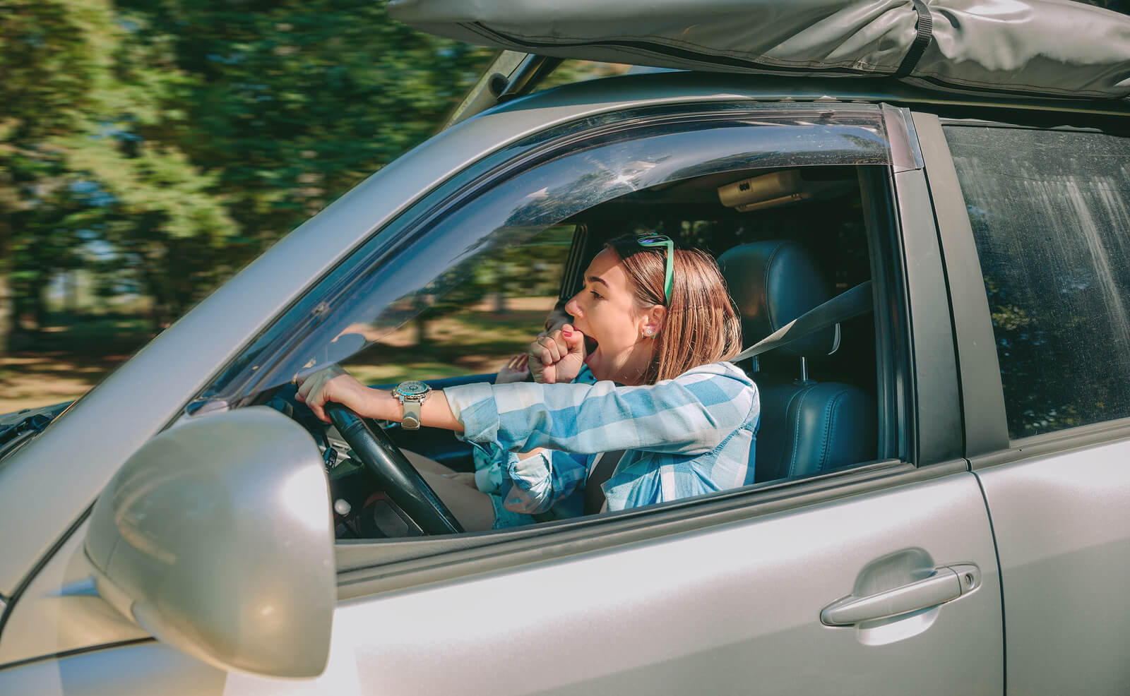 A woman yawning while driving